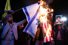 A man holds a photo of Iran's Supreme Leader, Mojtaba Khamenei, while the flags of the US and Israel are burnt, as people gather after a two-week ceasefire in the Iran war was announced, in Tehran, Iran, April 8, 2026. 