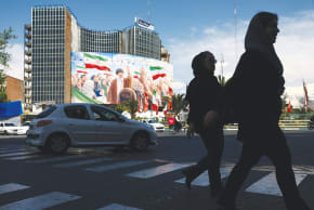 PEOPLE WALK past a billboard featuring an image of the late Supreme Leader of Iran, Ayatollah Ali Khamenei, on a building in Tehran, last week. 