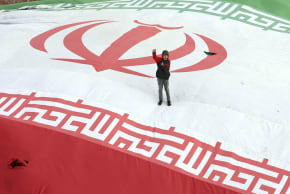 A boy raises his fist while standing on a giant Iranian flag during the funeral of Alireza Tangsiri, commander of the Iranian Revolutionary Guards' navy, alongside others killed in US-Israeli strikes on Iran at Enghelab Square in Tehran on April 1, 2026. 