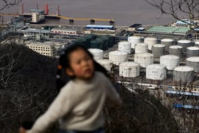 Un niño camina por una ruta de senderismo con los tanques de almacenamiento de petróleo y las instalaciones de CNOOC Ningbo Daxie Petrochemical Co., Ltd. al fondo, en Ningbo, Zhejiang (China), el 21 de marzo de 2026. 