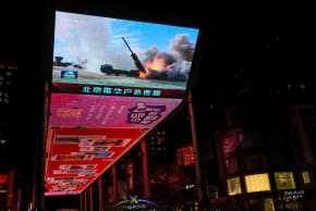 FILE PHOTO: A military aircraft is seen on a giant screen showing news footage about joint army, navy, air and rocket forces drills around Taiwan by the Chinese People's Liberation Army (PLA), outside a shopping mall in Beijing, China, April 1, 2025. 