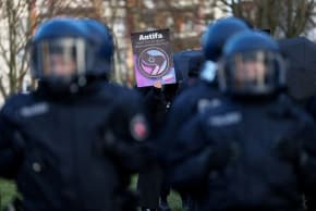 A demonstrator holds a placard with the slogan 'Antifa means fight against every antisemitism' and a logo of Germany's Die Linke (The Left) party, near police officers, during a protest against antisemitism, in Leipzig, Germany January 17, 2026. 