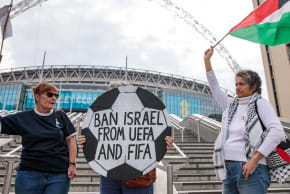 Pro-Palestinian activists protest with a football-shaped sign and a Palestinian flag outside Wembley Stadium on October 2nd, 2025 in London, United Kingdom.
