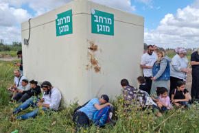 Israelis take cover around a small, overcrowded bomb shelter in a public park as sirens sound during Iranian missile attacks on April 6, 2026 in Hod Hasharon, central Israel.