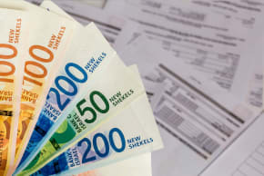 A bunch of Israeli New Shekel banknotes in the hand on the Bills background.Conceptual Image for Finance and Banking