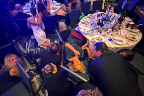 Guests take cover after U.S. President Donald Trump and first lady Melania Trump were rushed out of the White House Correspondents' Association dinner by Secret Service agents when a man opened fire with a shotgun on security personnel outside the room, in Washington, D.C., U.S. April 25, 2026.