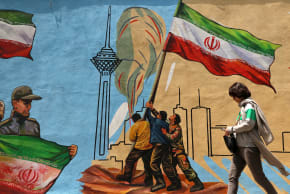 An Iranian woman walks past an anti-USA and anti-Israel mural, in Tehran on April 21 2026, amid a ceasefire in the region.  (photo credit:  ATTA KENARE / AFP via Getty Images)