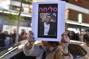 People gather outside a Pizza Hut branch in Petah Tikva, lighting candles and placing flowers in memory of employee Yemanu Binyamin Zalka, who was stabbed and later died of his wounds on the eve of Independence Day, April 25, 2026. 