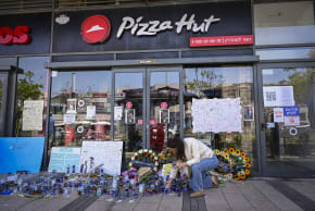 People gather outside a Pizza Hut branch in Petah Tikva, lighting candles and placing flowers in memory of employee Yemanu Binyamin Zalka, who was stabbed and later died of his wounds on the eve of Independence Day, April 27, 2026 (photo credit: AVSHALOM SASSONI/FLASH90)