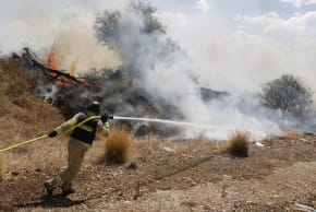 Firefighters douse flames in a field after a drone launched from southern Lebanon fell near Kibbutz Snir in the Upper Galilee.