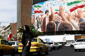 Una mujer pasa junto a una valla publicitaria en la que aparece una imagen del difunto líder supremo de Irán, el ayatolá Alí Jamenei, colocada en un edificio, en medio de un alto el fuego entre Estados Unidos e Irán, en Teherán, Irán, el 27 de abril de 2026 