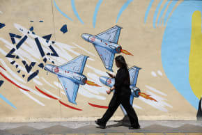 An Iranian woman walks next to an anti-Israeli mural on a street in Tehran, Iran, May 11, 2026. 