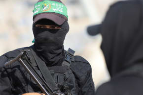 Hamas members look on as they escort members of the Red Cross towards an area within the yellow line, in Gaza City, November 12, 2025.  