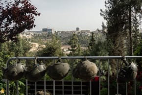 IDF soldiers' helmets are hung from a rail, with Jerusalem in the background, on Israel's Memorial Day on April 30, 2025 in Jerusalem, Israel.