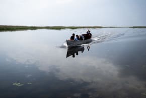 Fishermen ride in their boat through the Iraqi Hawizeh Marsh in Maysan province, southern Iraq, after water returned due to rainfall following a long period of drought on April 26, 2026. 