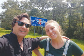 The writer and daughter Noa O’Sullivan on roots visit to Mississippi, 2018. Background: Highway welcome sign upon entering to state, ‘the birthplace of America’s music.’ 