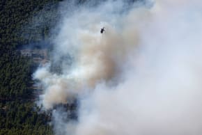 A firefighting helicopter flies over wildfire near the village Agia Paraskevi, Greece, August 2, 2026.