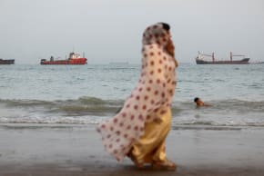 FILE PHOTO: People walk on the beach, with vessels in the Strait of Hormuz visible near the beach of Bandar Abbas, Iran, May 22, 2026.