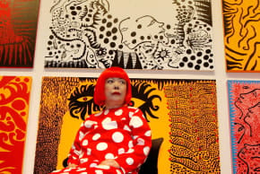 Artist Yayoi Kusama poses for a photograph with her artwork "Love arrives at the Earth Carrying with it a Tale of the Cosmos" at the Tate Modern gallery in London