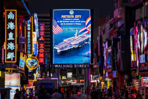 People walk past an LED display welcoming U.S. service personnel from the U.S. Nimitz-class aircraft carrier USS Abraham Lincoln, which is docked at Laem Chabang Port for a rest stop following a long deployment in the Middle East, in Pattaya City, Thailand, September 3, 2026.