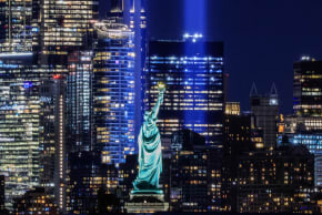 The Statue of Liberty stands in the foreground as the ‘Tribute in Light’ public art installation commemorating the September 11, 2001, attacks shines from the Lower Manhattan skyline on September 11, 2026.