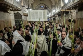 Jewish men covered in prayer shawls hold the Four Species, palm, citron, myrtle and willow as they take part in Shacharit morning prayers during the Jewish holiday of Sukkot, at the entrance to the Temple Mount in Jerusalem’s Old City, September 27, 2026.