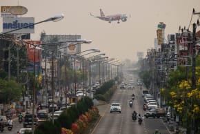 A passenger plane prepares to land at the airport as commuters drive on the road below on a heavily polluted day in Chiang Mai on April 2, 2026