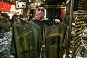 A shop assistant, who refused to be identified, displays T-shirts presenting the official logotype of radical Islamic Shiite group Hezbollah (L) and another of Lebanese Army´s special forces (R), on sale at an army and navy police supply shop, in Sao Paulo, Brazil, July 28, 2006.