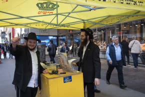 Shmuel Cohen (left) takes a break from wrapping tefillin with passersby in New York City's Diamond District on October 23, 2026. 