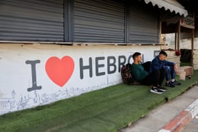Palestinians sit near the closed entrance of Hebron, in the West Bank, October 24, 2026.