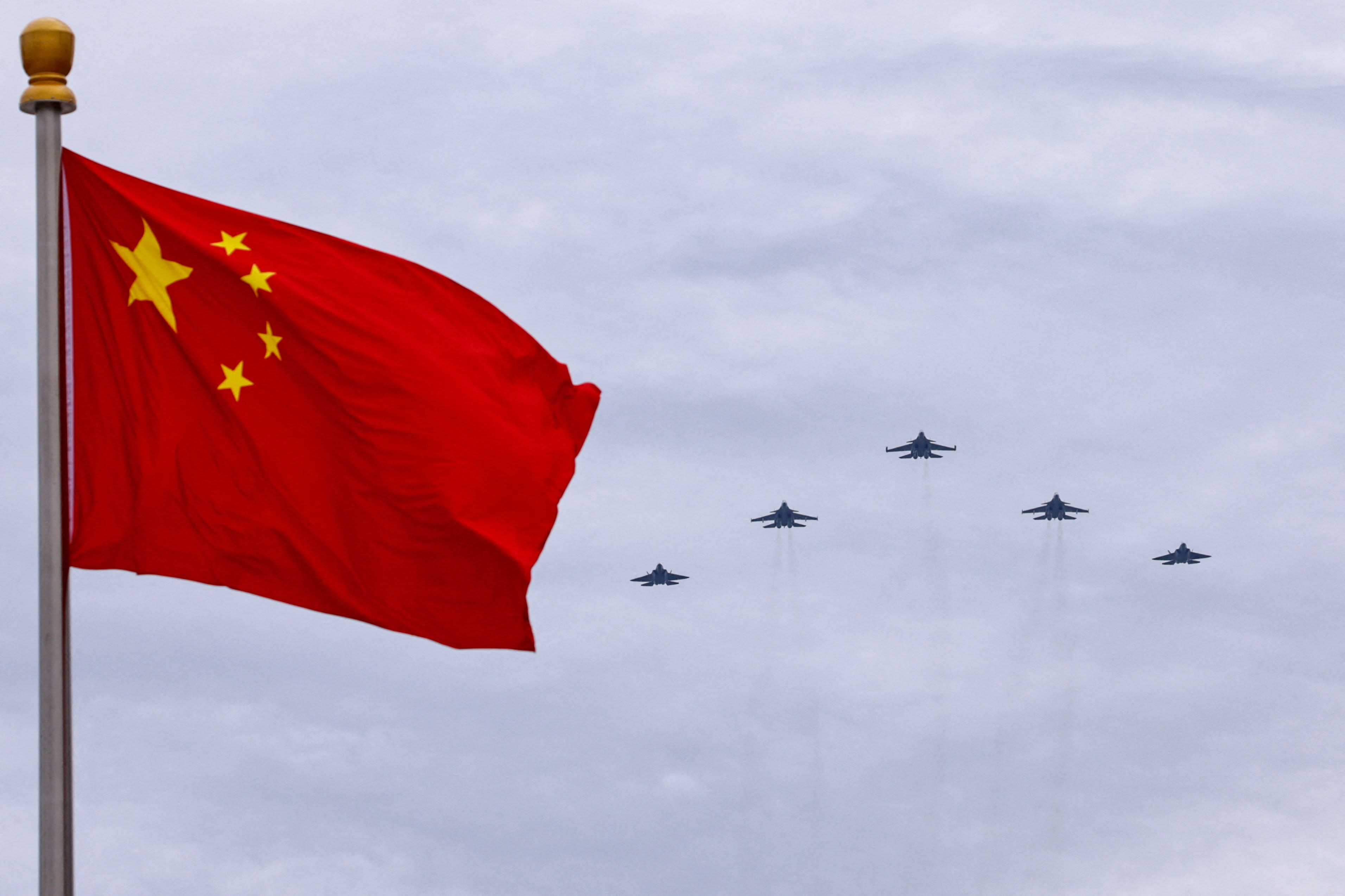 Shenyang J-16, Chengdu J-20 and Shenyang J-35 fighter jets fly in a formation past a Chinese national flag during a flyover rehearsal ahead of a military parade to mark the 80th anniversary of the end of World War Two, in Beijing, China, August 24, 2025.  (photo credit: REUTERS/TINGSHU WANG)