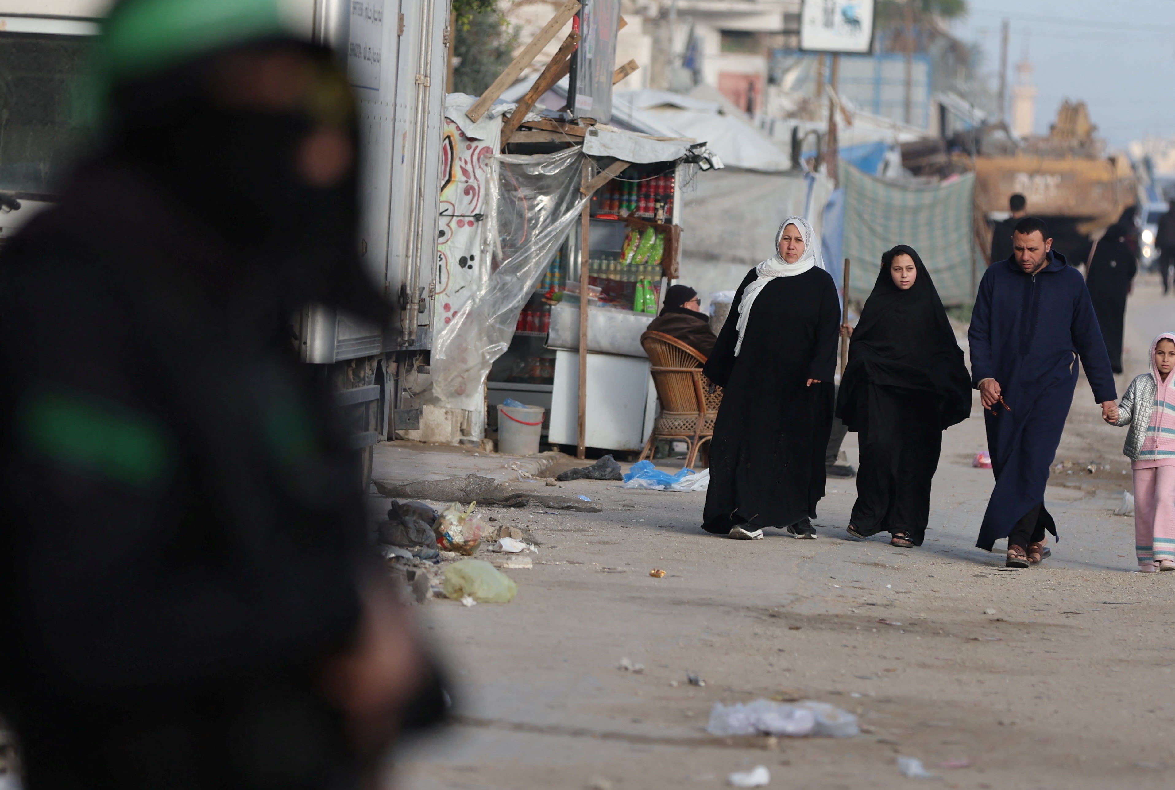 A Hamas terorrist stands guard as Palestinians walk on a street during Eid al-Fitr, in Gaza City, March 20, 2026.  (photo credit: Dawoud Abu Alkas/Reuters)