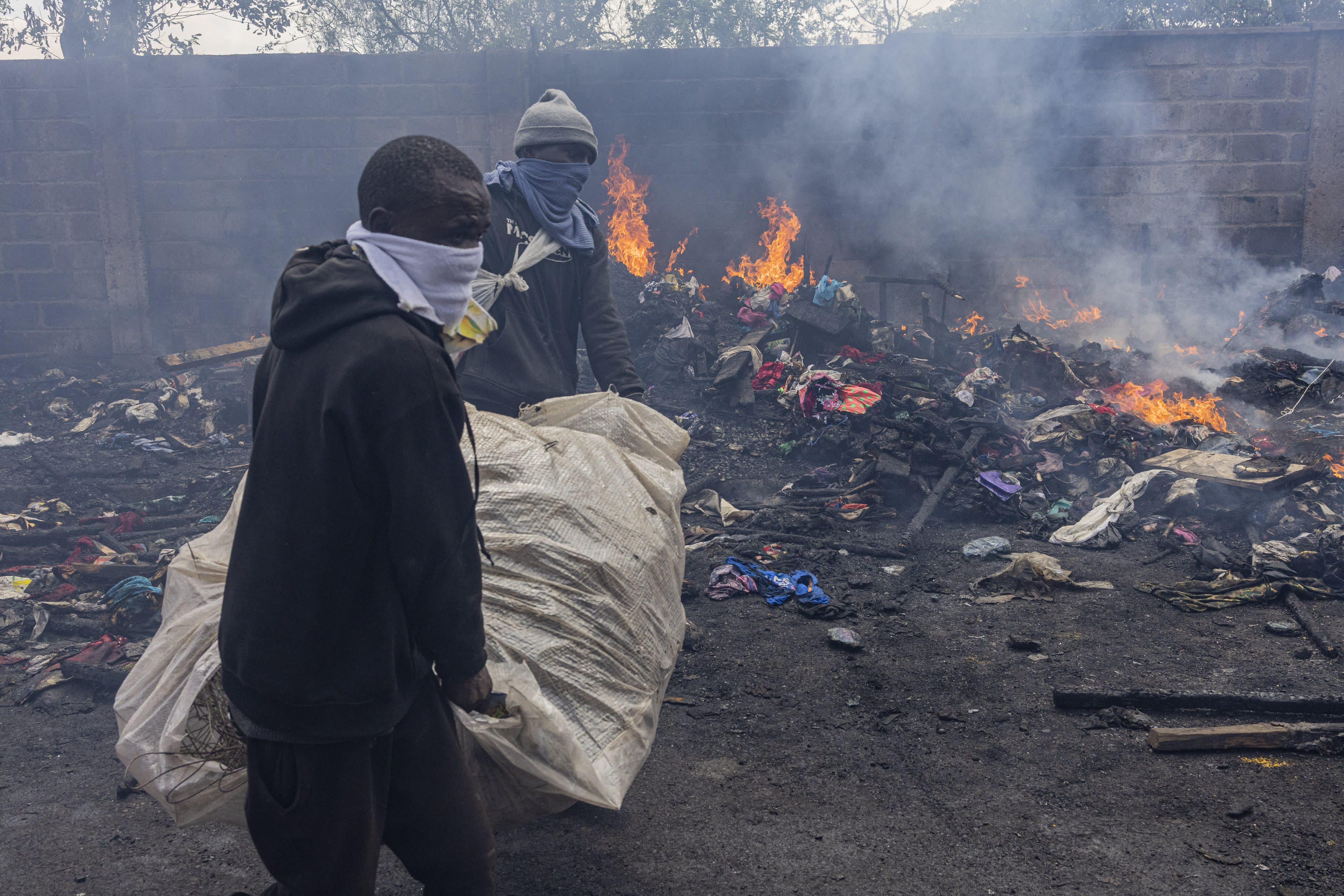 Traders scavenge clothes from debris burnt down by the fire at Toi market, a second hand clothing market, in Nairobi March 16, 2026. According to a police report, the fire was caused by an electricity fault that razed about 250 stalls of second hand clothes. (photo credit: SIMON MAINA/AFP via Getty Images)