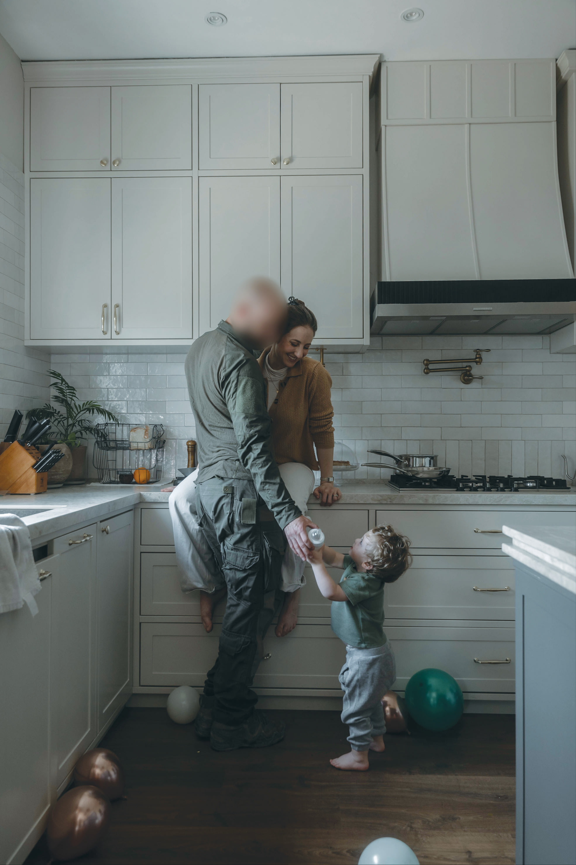 A FLEETING moment of calm: Shiri and her husband share a quiet exchange in the kitchen with their child, one of the ‘little things’ that hold a family together between deployments. (photo credit: Chen G. Schimmel)