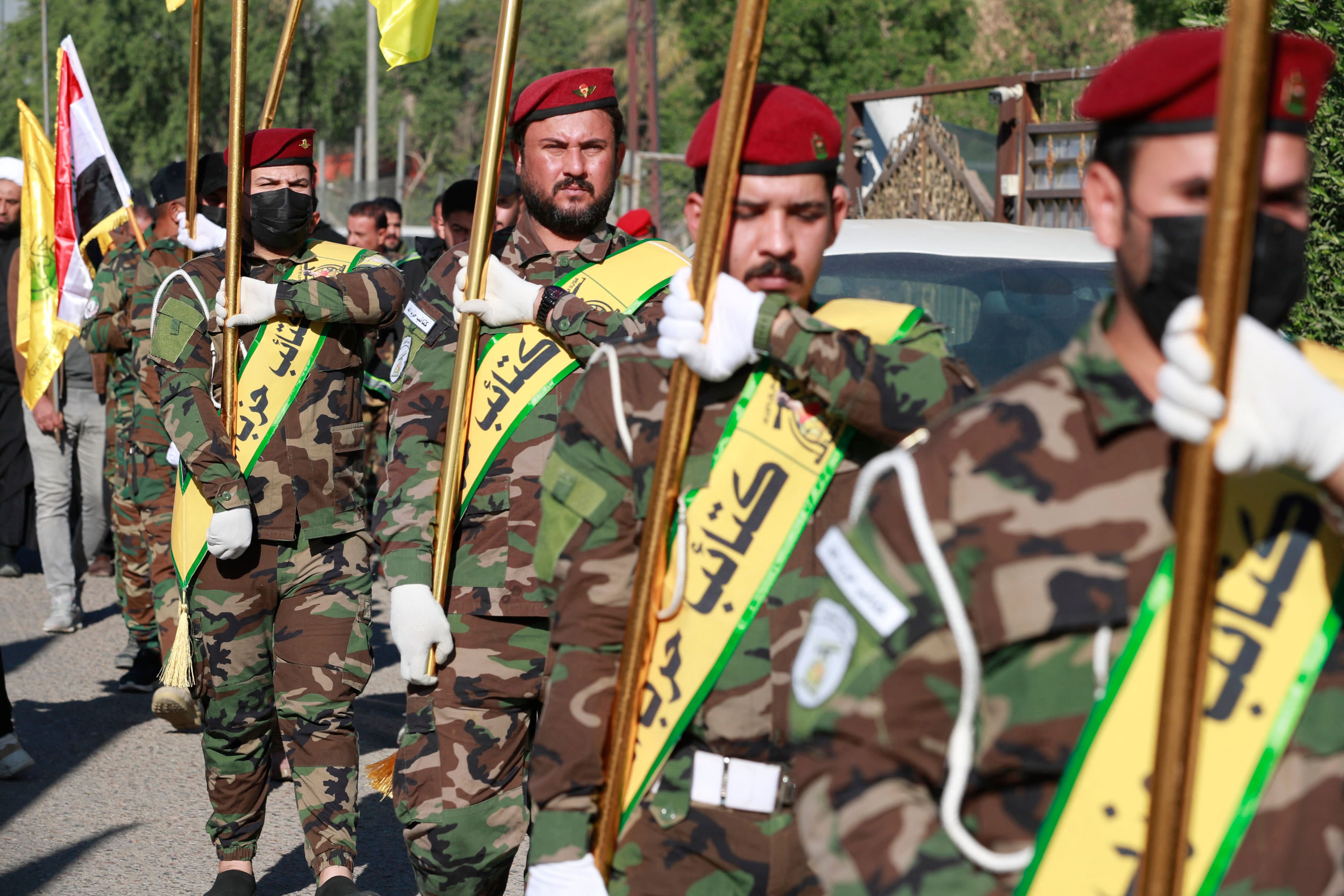 Fighters lift flags of Iraq and paramilitary groups, including al-Nujaba and Kataib Hezbollah, during a funeral in Baghdad for five militants killed a day earlier in a US strike in northern Iraq, on December 4, 2023. (photo credit: Ahmad al-Rubaye/AFP via Getty Images)