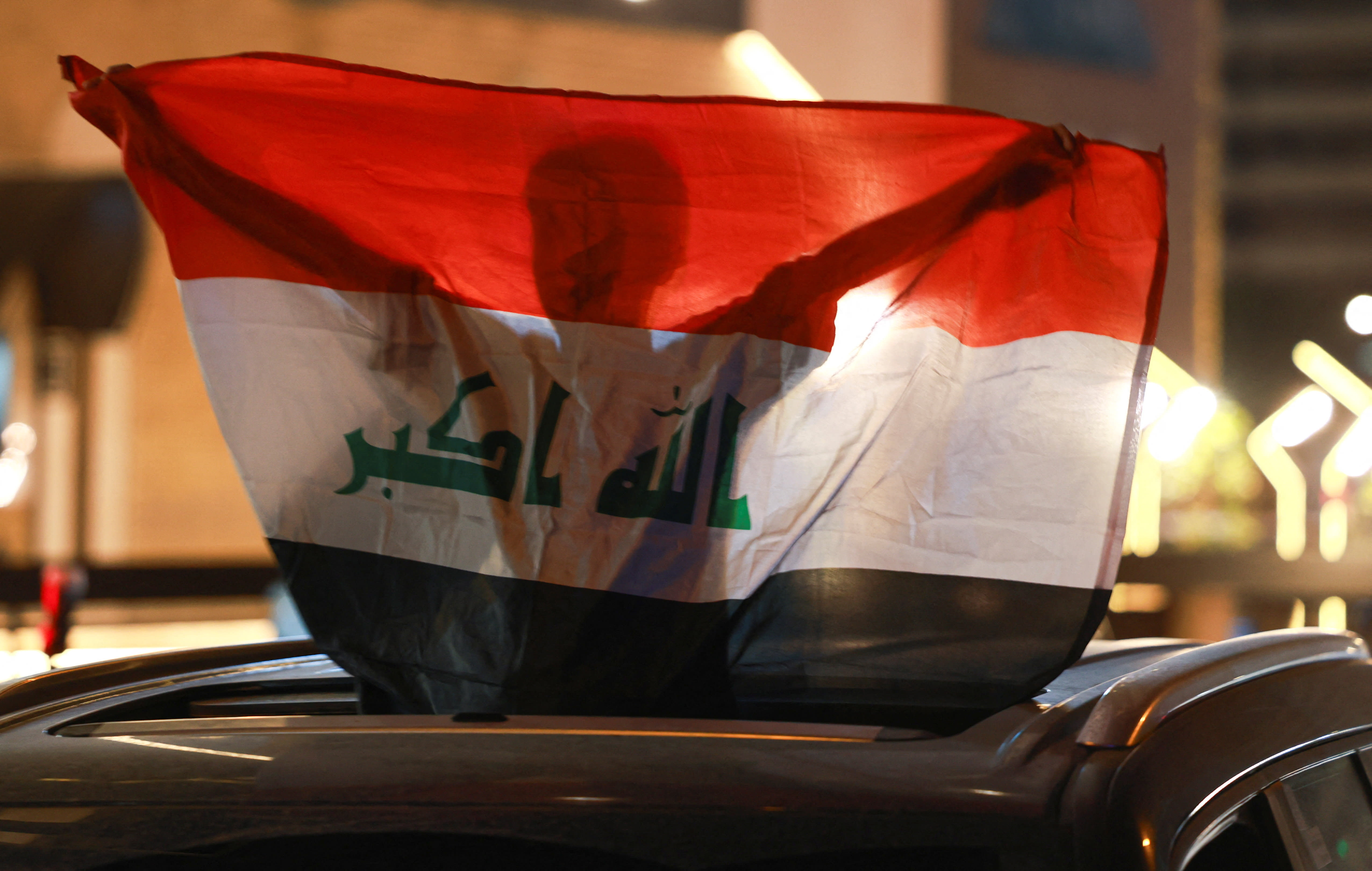 A boy holds an Iraqi flag near the Iranian embassy during a gathering following the announcement of a ceasefire between Iran and the United States, in Baghdad, Iraq, April 8, 2026.  (photo credit: REUTERS/AHMED SAAD)