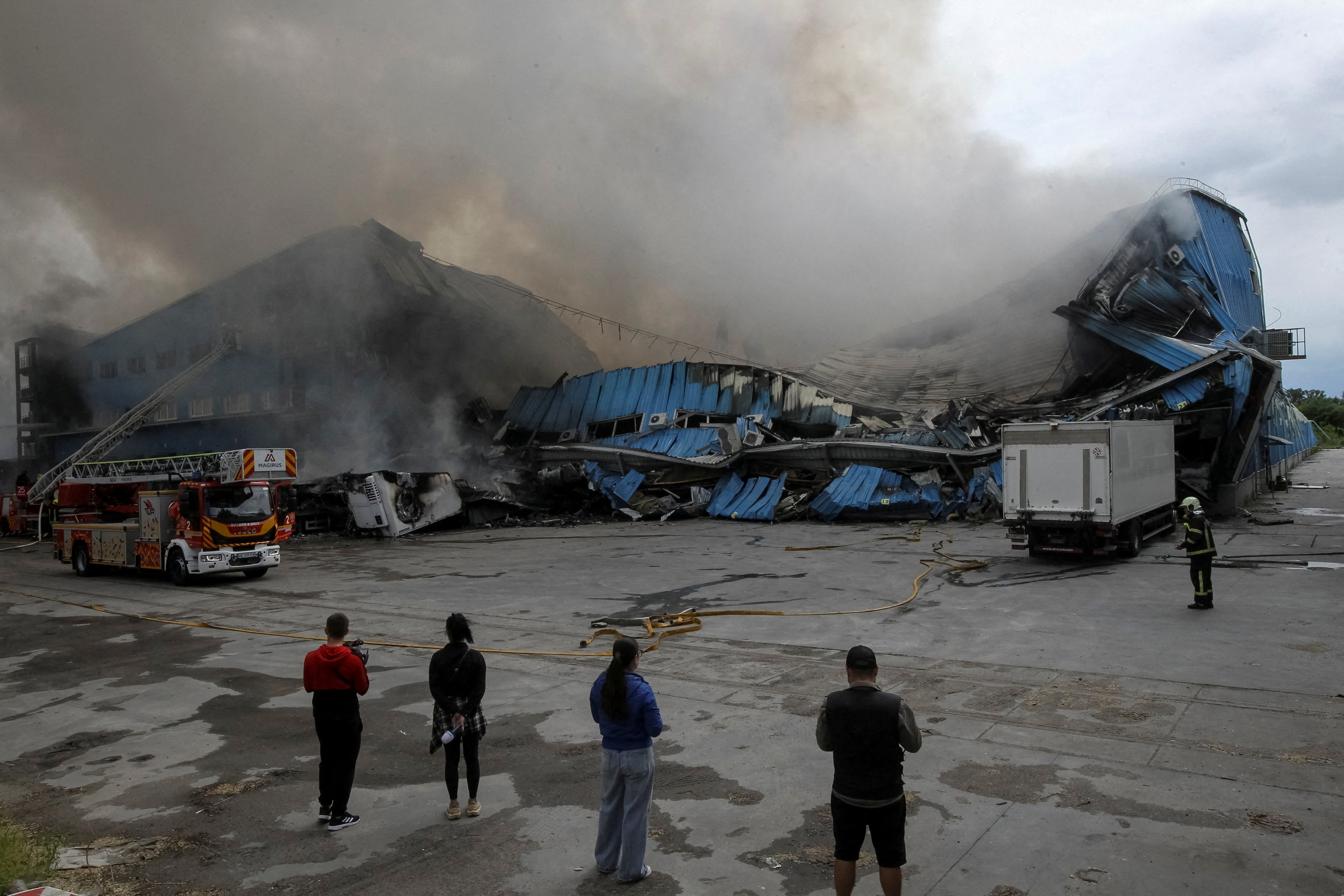 Firefighters and journalists work at a site of a Russian drone strike, amid Russia