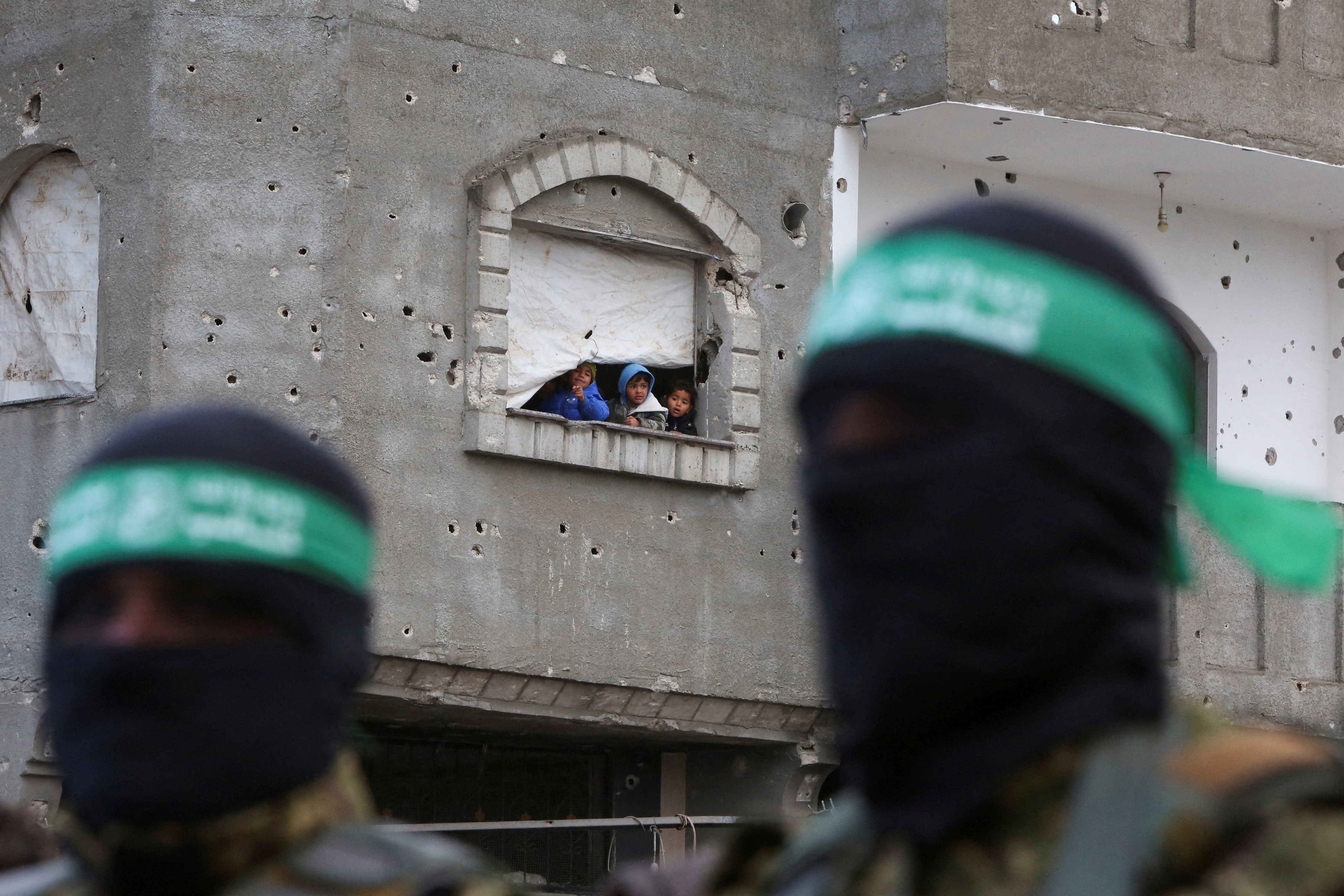  Children look out of a building as Palestinian Hamas terrorists stand guard on the day of the handover of hostages, including those held in Gaza since the deadly October 7 2023 attack, February 22, 2025.  (photo credit:  REUTERS/Hatem Khaled TPX IMAGES OF THE DAY)