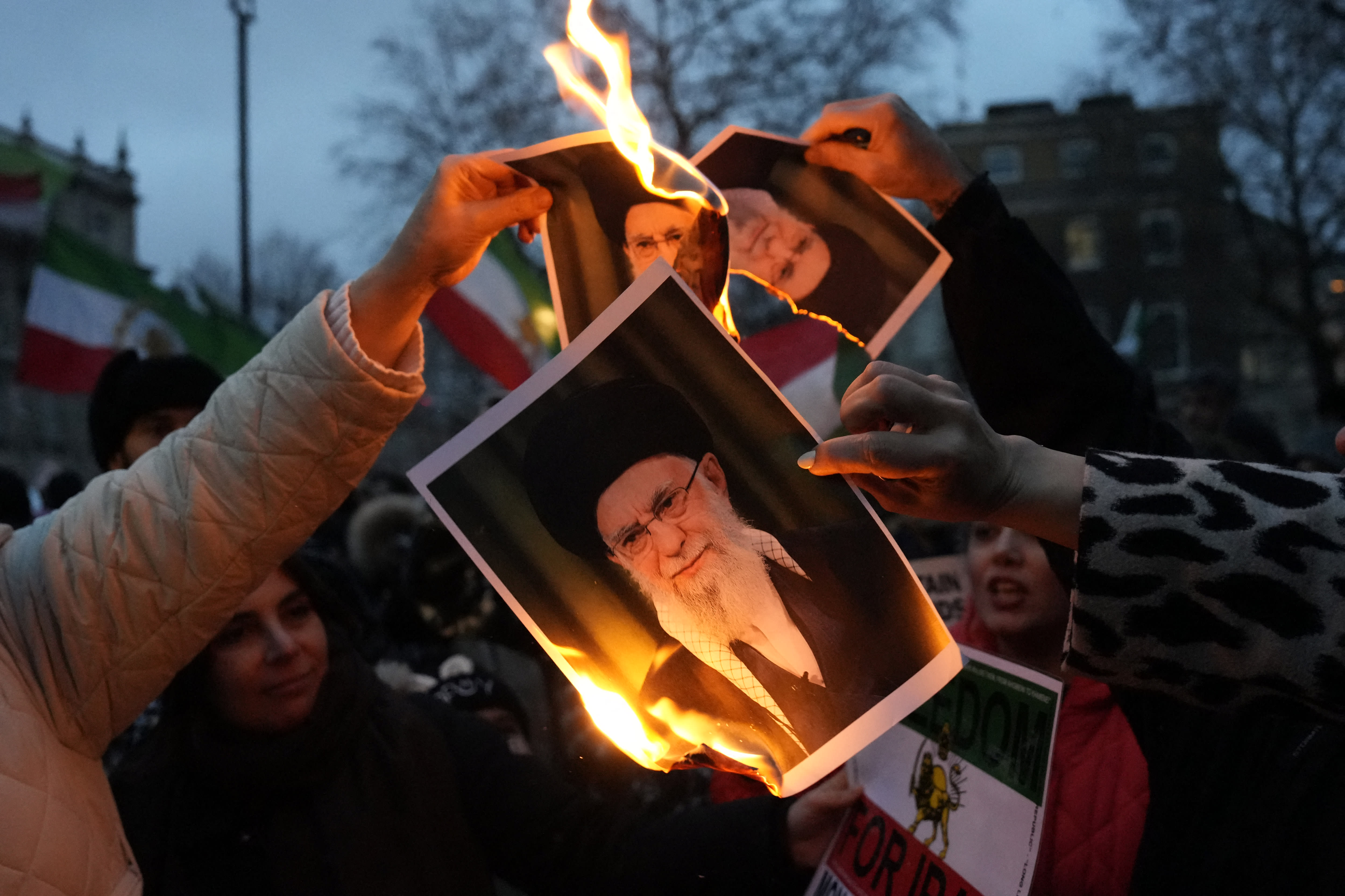 Protestors burn images of Ayatollah Ali Khamenei during a rally held in Solidarity with Iran