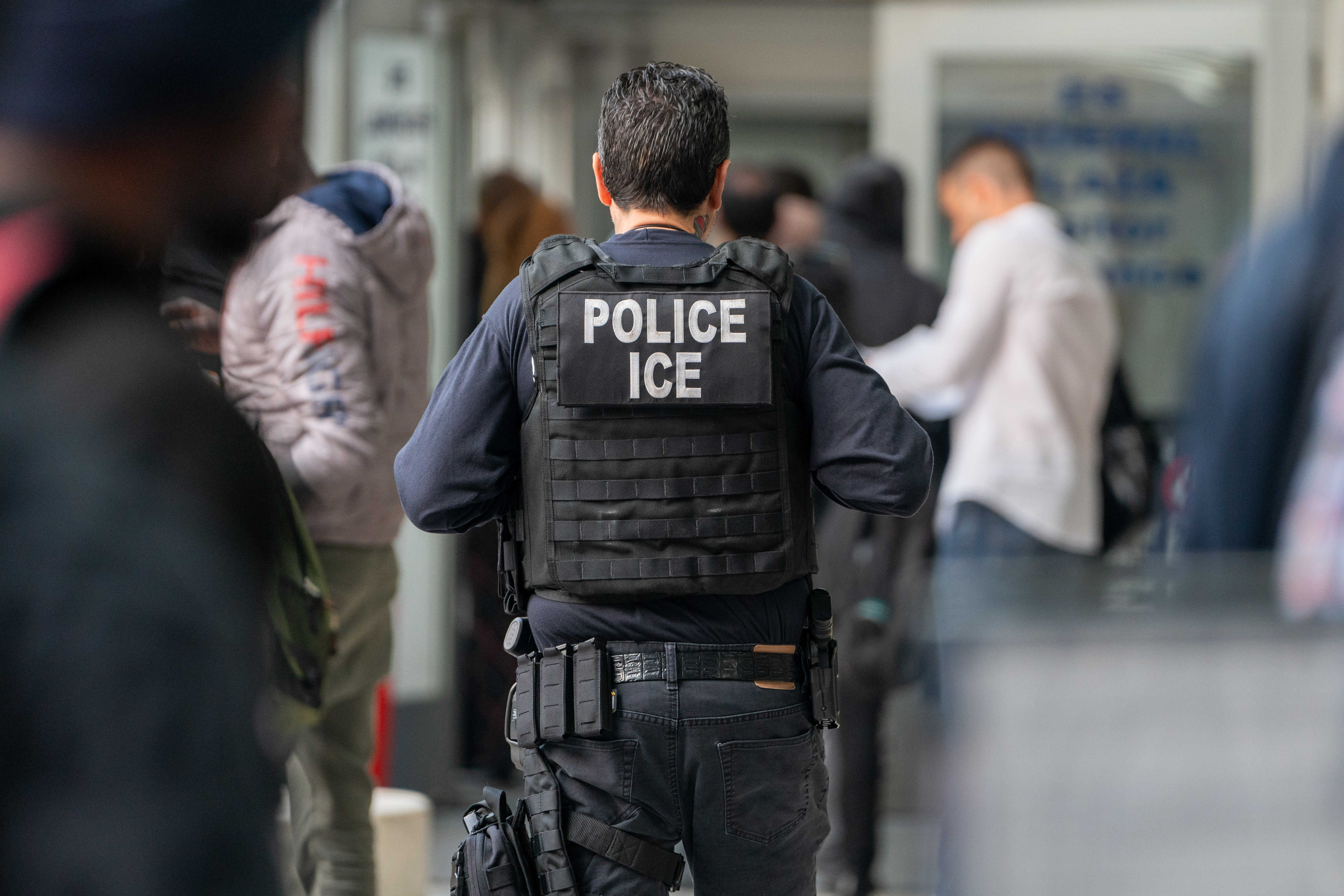 An ICE agent monitors hundreds of asylum seekers being processed upon entering the Jacob K. Javits Federal Building on June 6, 2023 in New York City; Illustrative. (photo credit: David Dee Delgado/Getty Images)