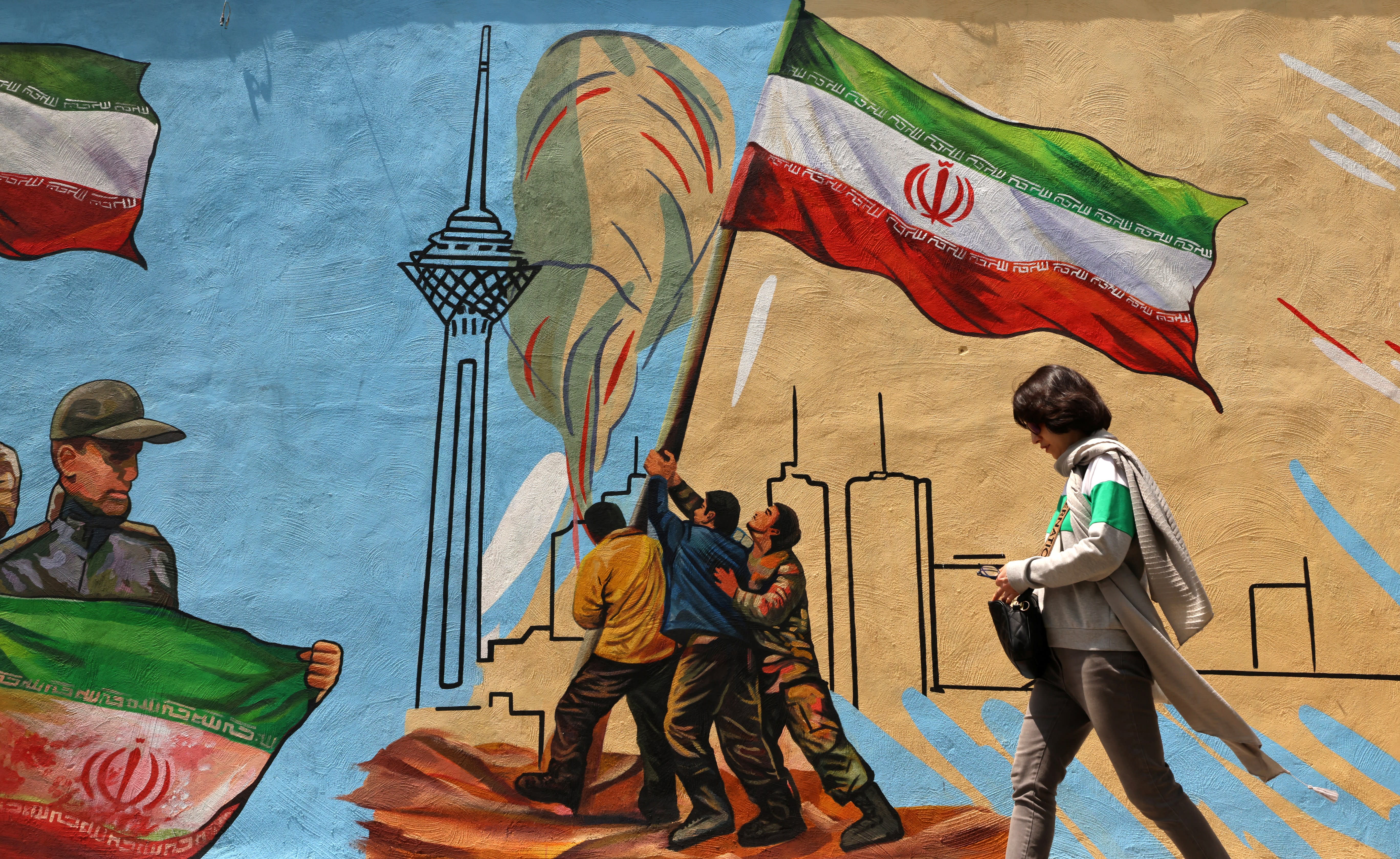 An Iranian woman walks past an anti-USA and anti-Israel mural, in Tehran on April 21 2026, amid a ceasefire in the region.  (photo credit:  ATTA KENARE / AFP via Getty Images)