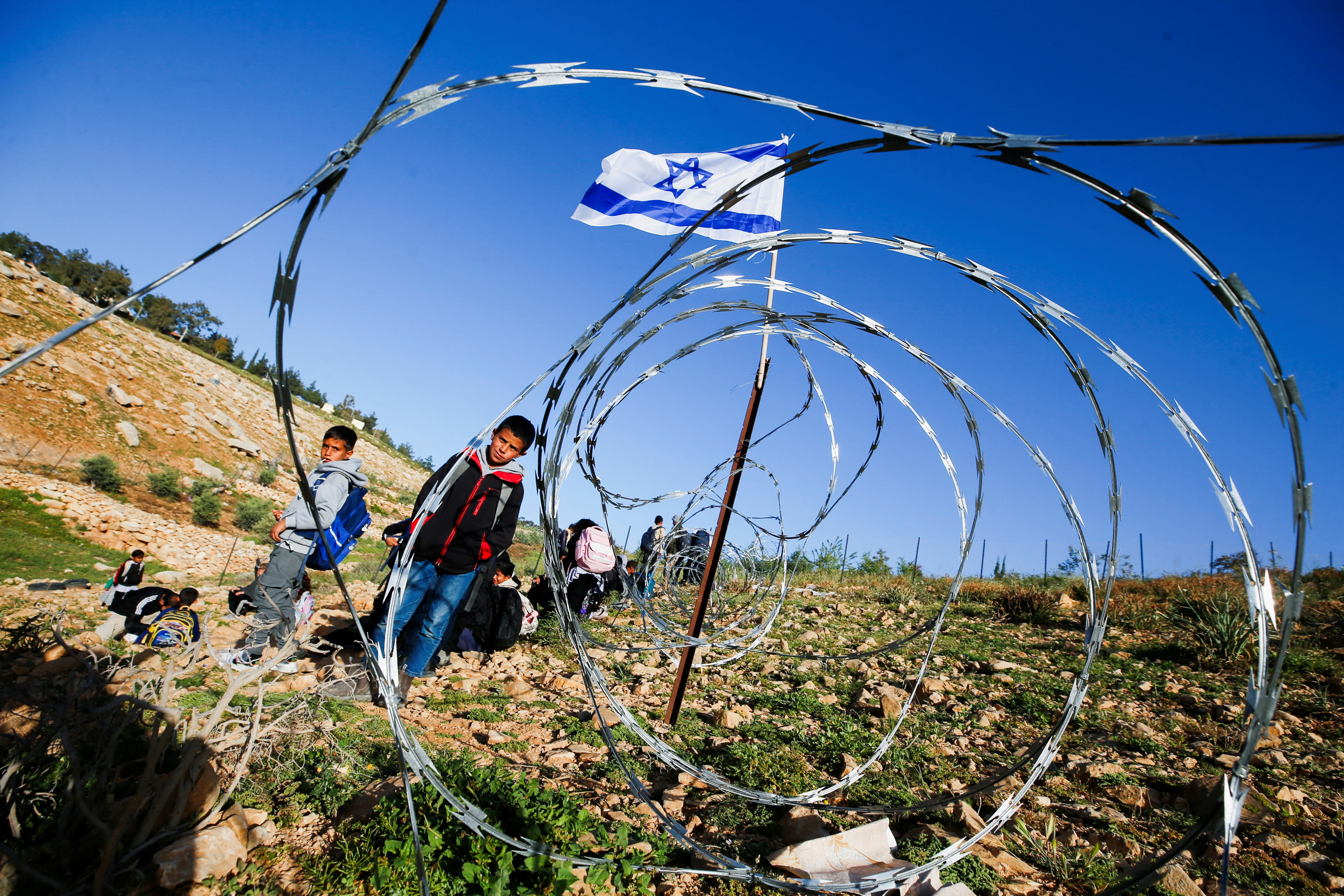 PALESTINIAN STUDENTS gather near a fence installed by Israeli settlers on their way to school, near Umm al-Khair in the West Bank, on April 14, 2026. (photo credit: YOSRI ALJAMAL/REUTERS)