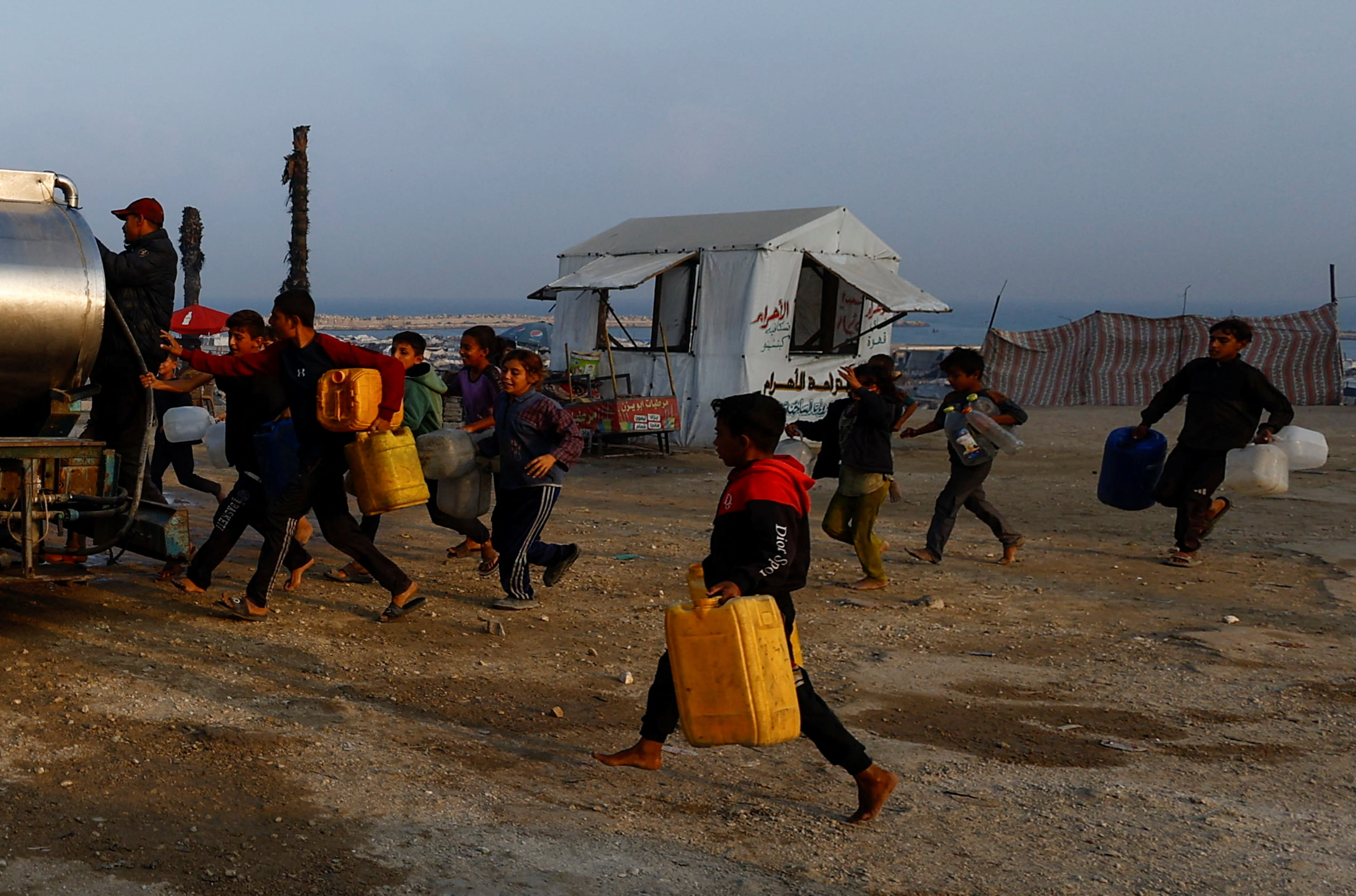 Displaced Palestinians run to fill containers with water amid a ceasefire between Israel and Hamas, in Gaza City, November 6, 2025.  (photo credit: REUTERS/Mahmoud Issa)