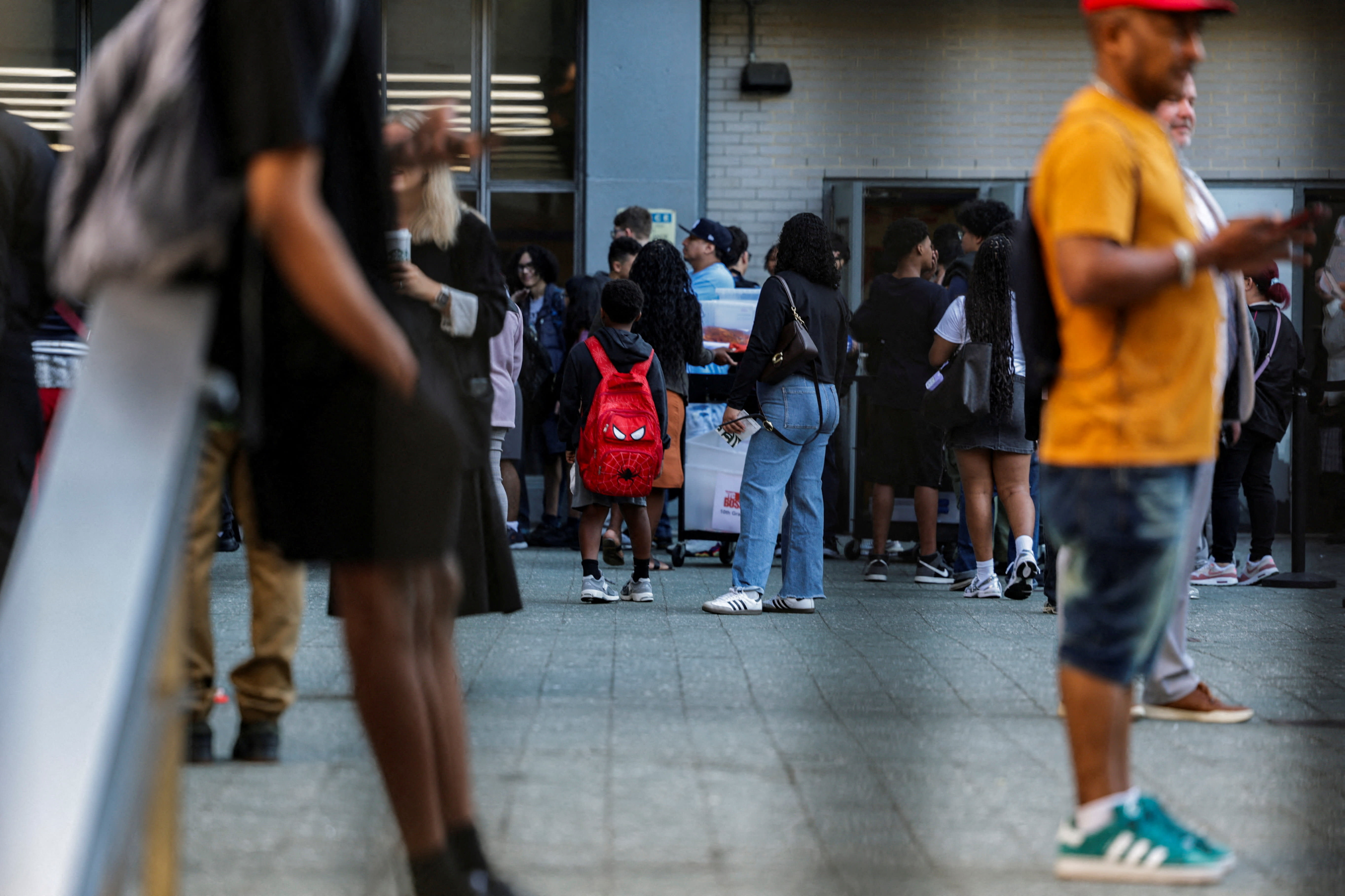 Students wait a line to enter the school on the first day of classes at New York City public schools in Manhattan, US, September 4, 2025. (photo credit: JEENAH MOON/REUTERS)