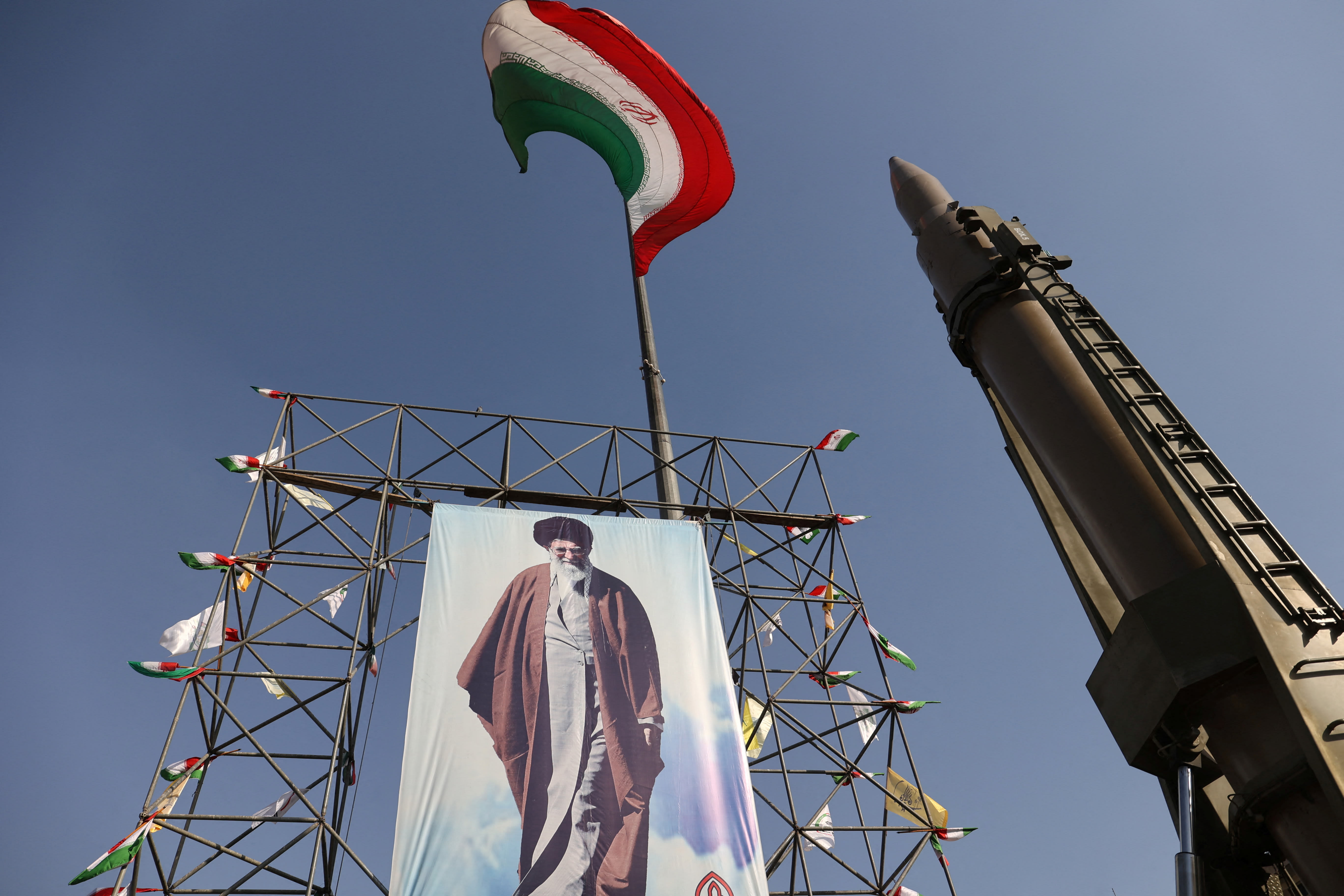  An Iranian missile system is displayed next to a banner with a picture of Iran