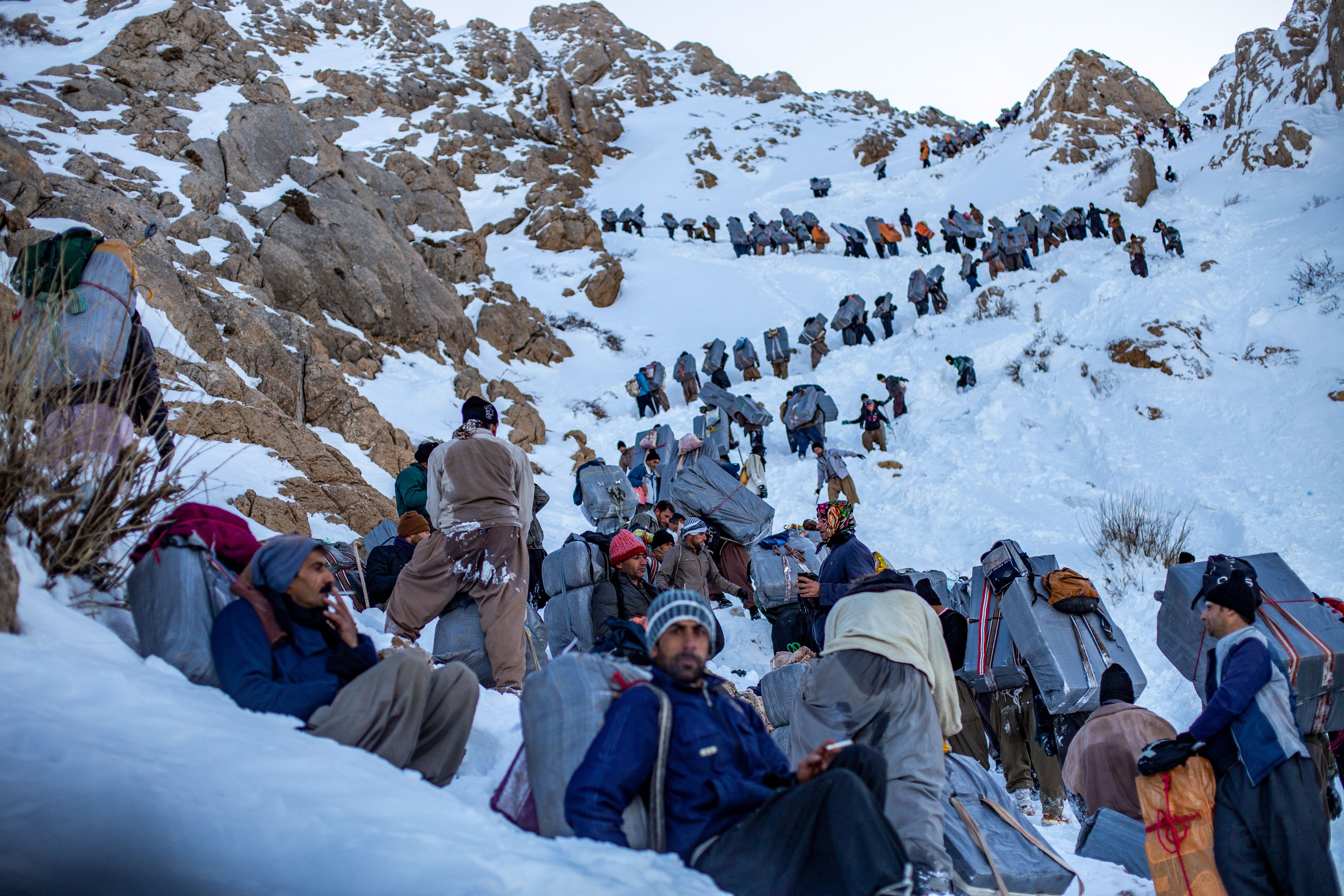 Kurdish men carry goods on their backs along the mountains of the Iran-Iraq border; illustrative. (photo credit: ABED JALILPOURAN/Middle East Images/AFP via Getty Images)