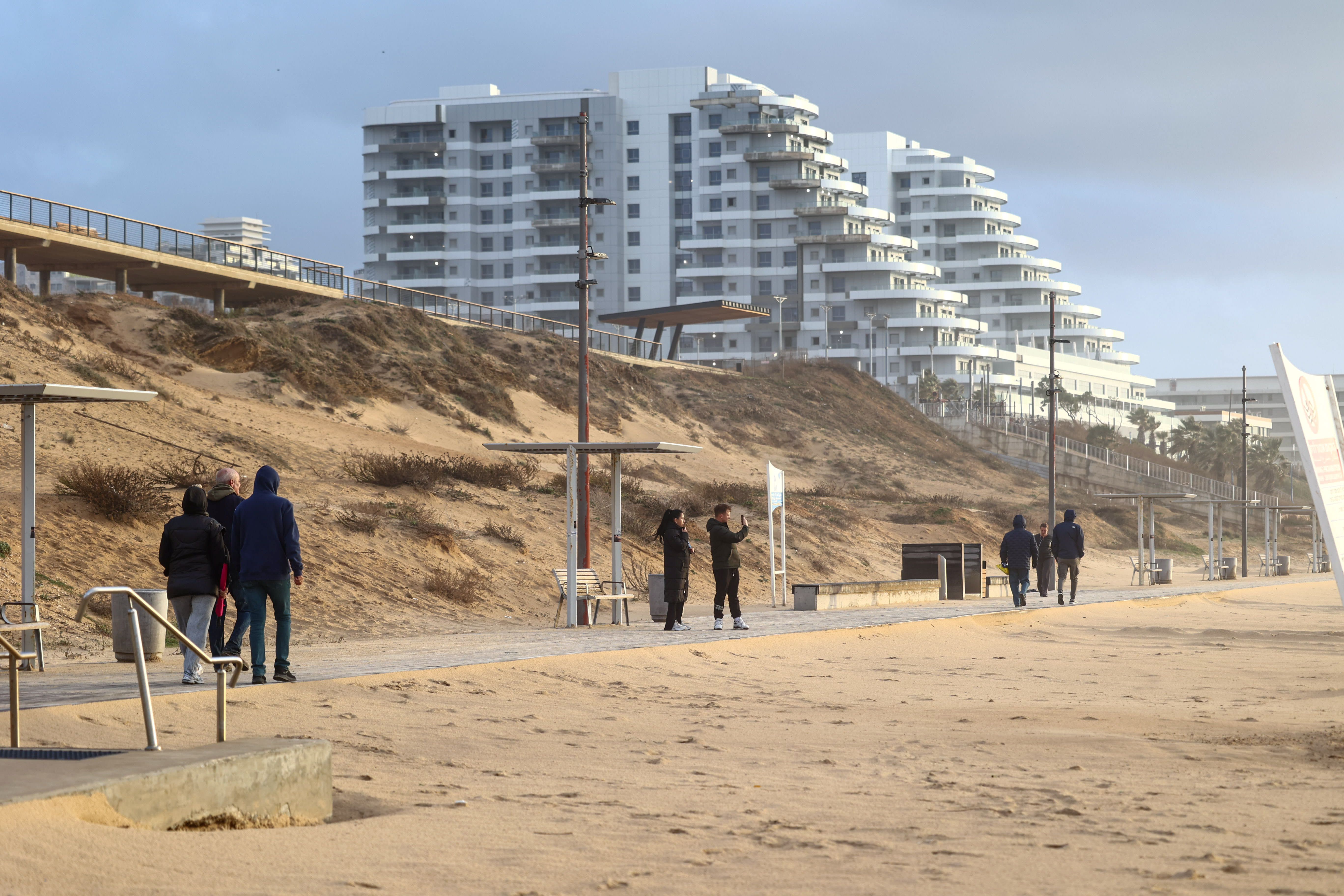 People walk at the beach in Bat Yam, central Israel, on a cold winter day, January 9, 2026. (photo credit: Dor Pazuelo/Flash90)