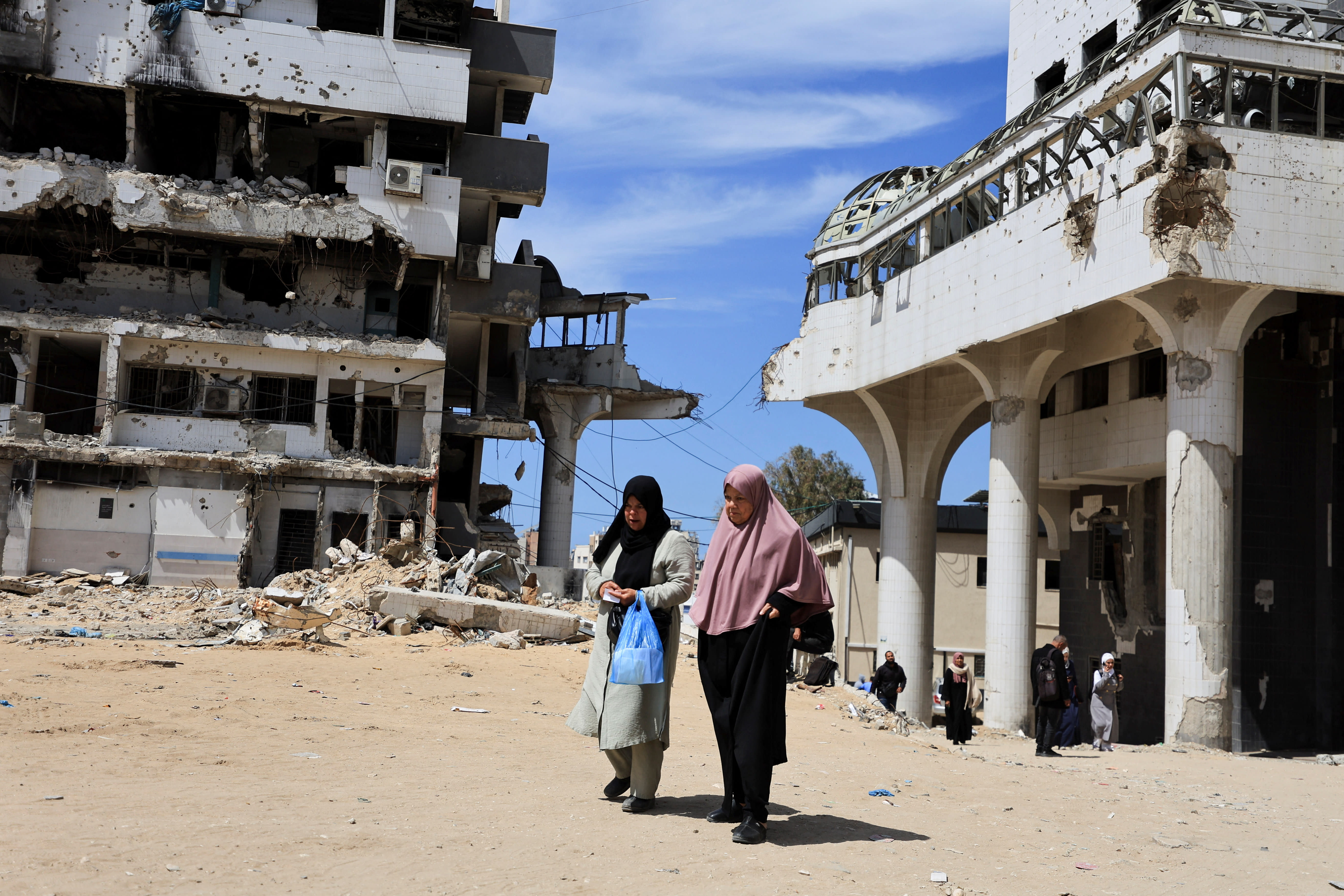 Palestinian women walk past buildings damaged during the war at Al-Shifa Hospital in Gaza City, Gaza, March 31, 2026. (photo credit: REUTERS/DAWOUD ABU ALKAS)