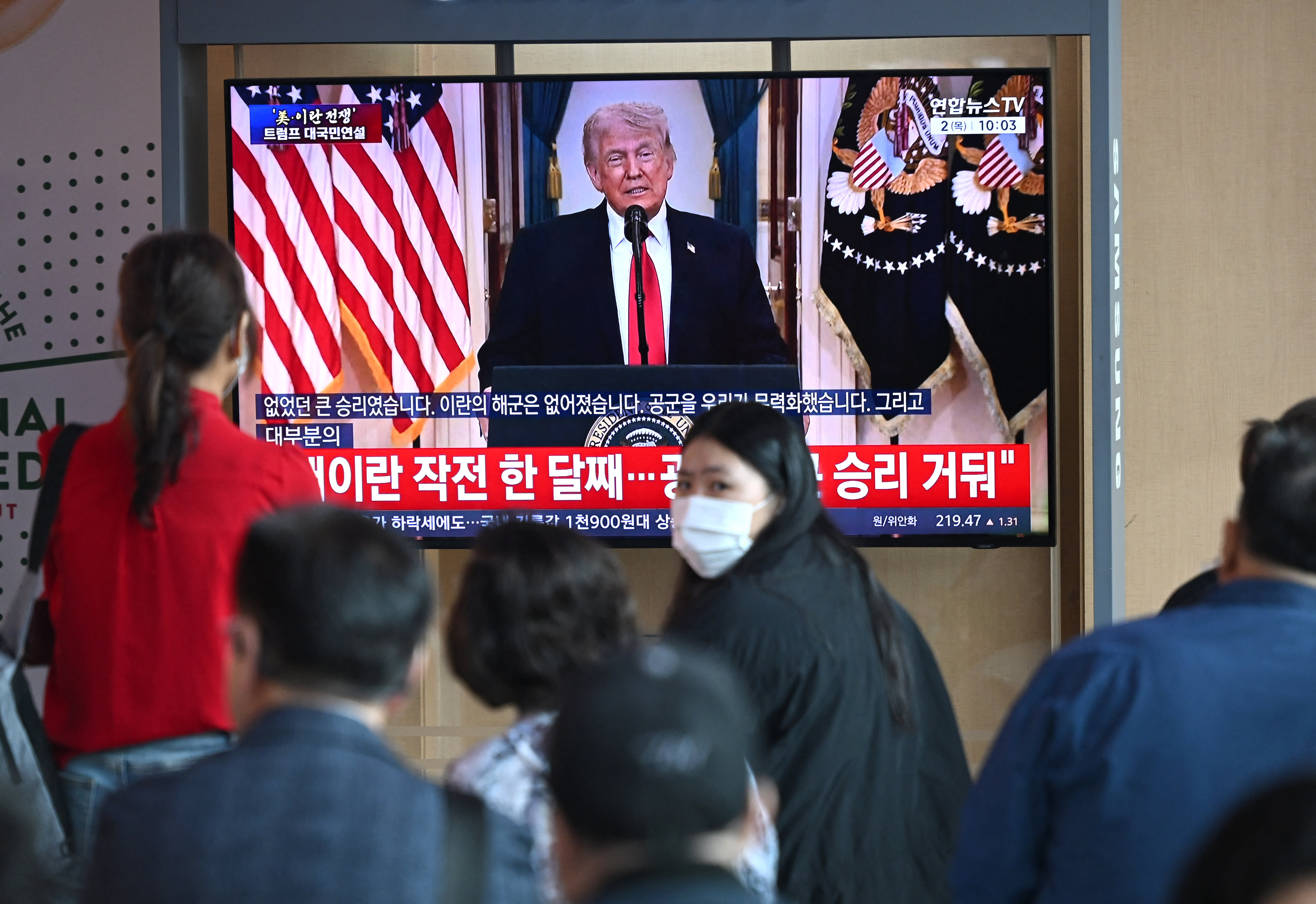 People watch a television screen showing a live broadcast of US President Donald Trump delivering national address on war against Iran, at a train station in Seoul on April 2, 2026. (photo credit: Jung Yeon-je / AFP via Getty Images)