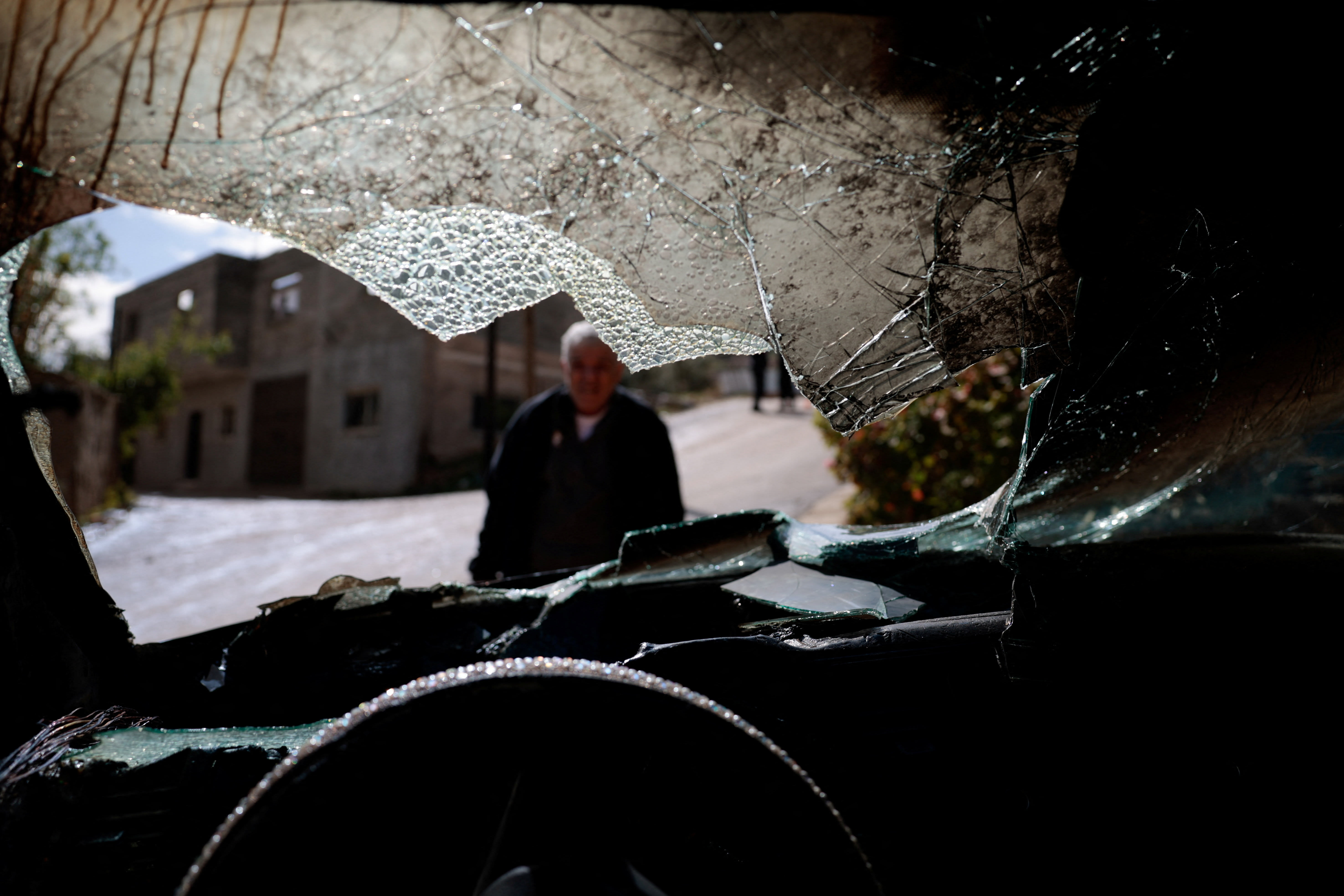 A man looks at a damaged vehicle, which Palestinians say was burned by Israeli settlers last night, in Al-Fandaqumiya, near Jenin, in the West Bank, March 22, 2026. (photo credit: REUTERS/Mohammed Torokman)